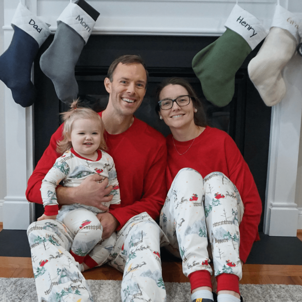 Melissa and her family sit in front of a fire in Christmas pajamas