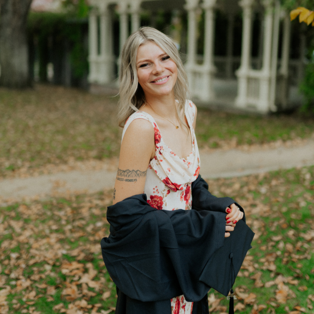 Holly in a grad gown in front of a lawn