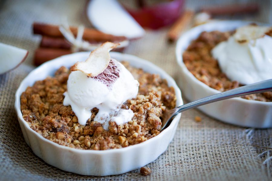 A bowl of apple crumble with a scoop of ice cream on top. 